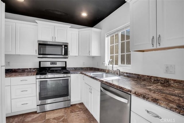 kitchen with recessed lighting, stainless steel appliances, a sink, white cabinetry, and stone finish flooring