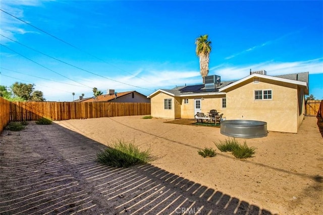 back of house featuring a patio area, solar panels, a fenced backyard, and stucco siding