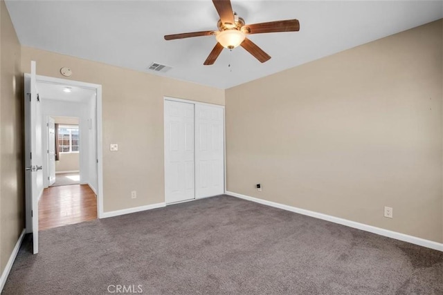 unfurnished bedroom featuring carpet floors, a closet, visible vents, ceiling fan, and baseboards