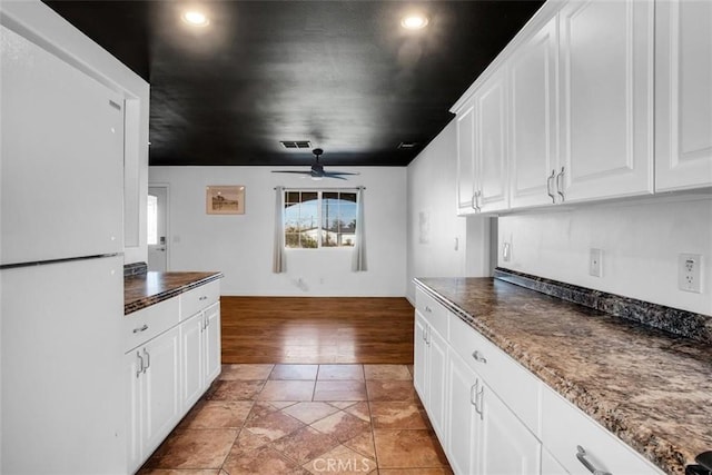 kitchen with visible vents, white cabinets, freestanding refrigerator, and a ceiling fan