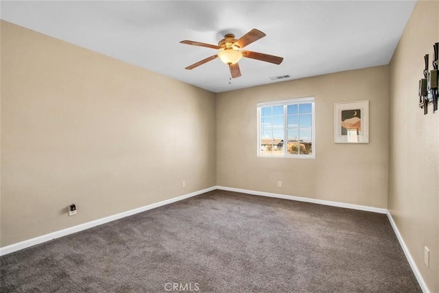 spare room with ceiling fan, dark colored carpet, visible vents, and baseboards