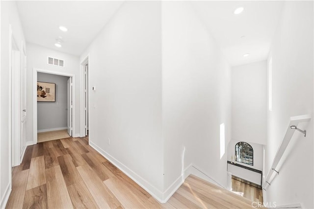 corridor featuring light wood-style floors, baseboards, visible vents, and recessed lighting