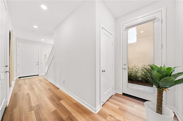 corridor with stairs, light wood-type flooring, baseboards, and recessed lighting