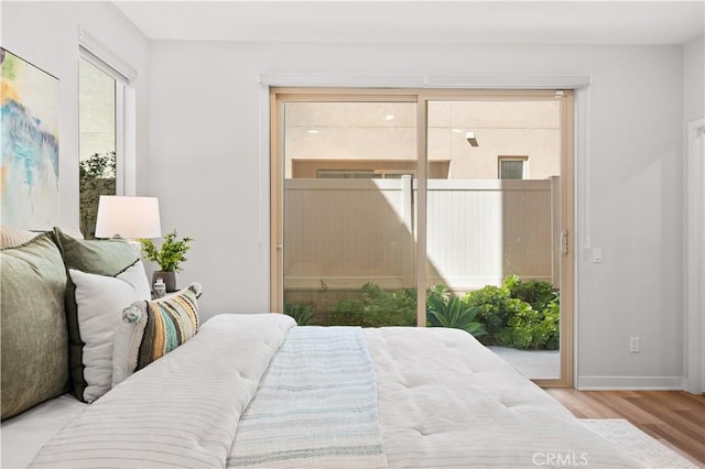 bedroom featuring access to outside, baseboards, and wood finished floors