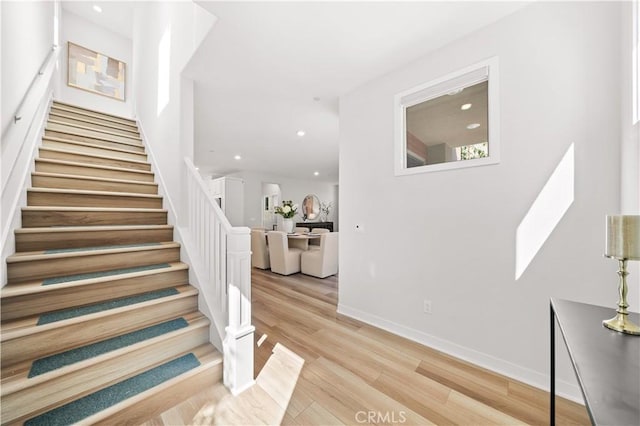 stairs with baseboards, wood finished floors, and recessed lighting