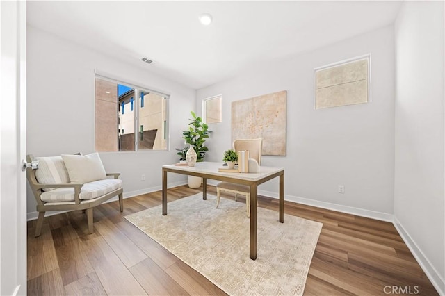 home office featuring wood finished floors, visible vents, and baseboards