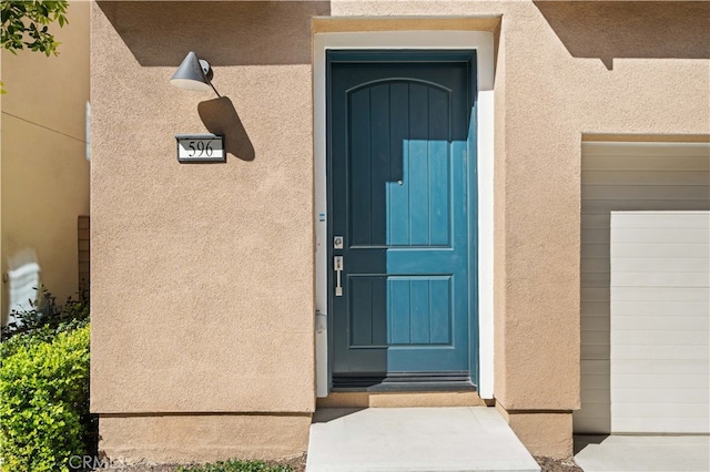 property entrance with a garage and stucco siding