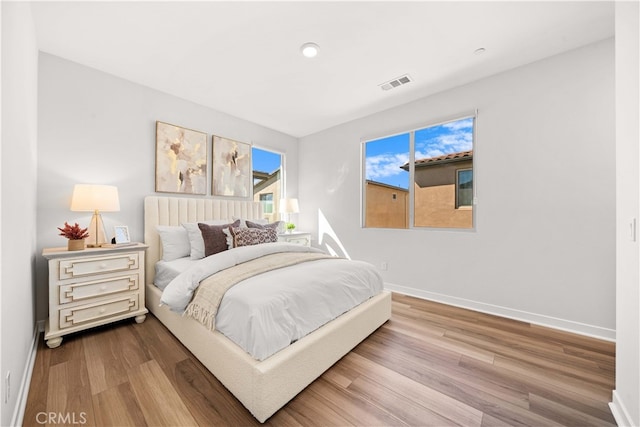 bedroom with wood finished floors, visible vents, and baseboards