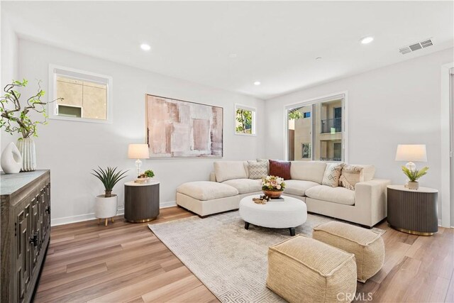 living room featuring light wood-type flooring, visible vents, and recessed lighting