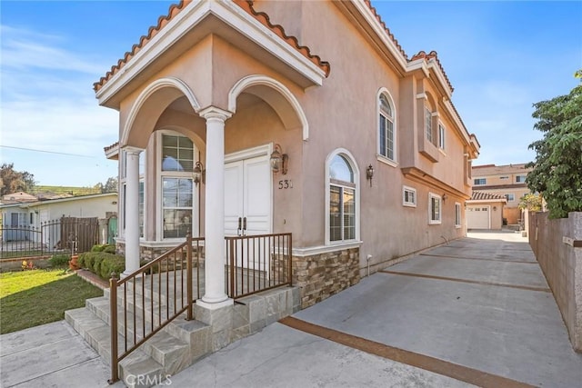 view of front of property featuring an outbuilding, stone siding, fence, and stucco siding