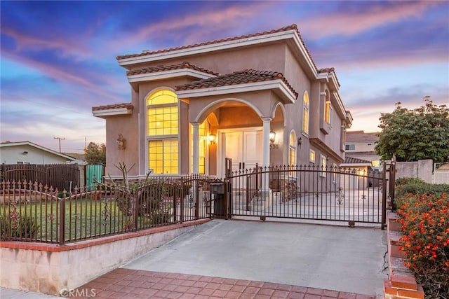 mediterranean / spanish-style house with a fenced front yard, a gate, and stucco siding
