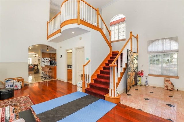 entrance foyer featuring stairway, baseboards, arched walkways, and wood finished floors