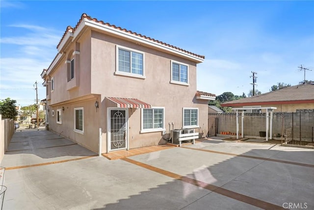 rear view of house featuring a patio area, fence, central AC, and stucco siding