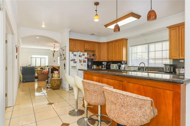 kitchen featuring tasteful backsplash, arched walkways, a sink, and light tile patterned floors
