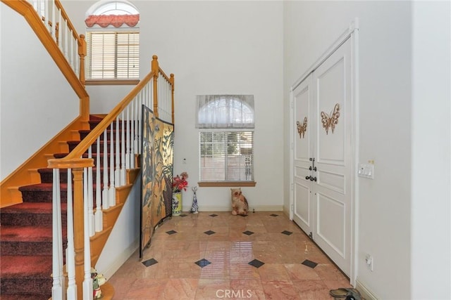entrance foyer featuring a towering ceiling, stairway, and baseboards
