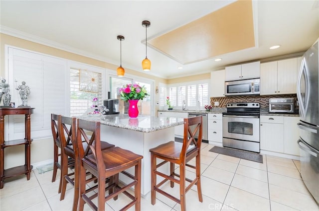 kitchen with appliances with stainless steel finishes, crown molding, decorative backsplash, and a kitchen breakfast bar