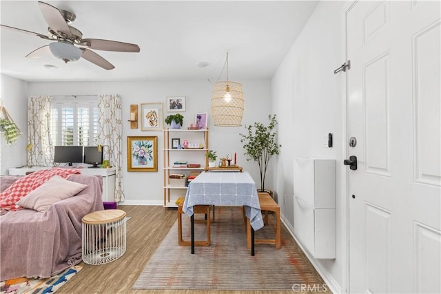 dining area with ceiling fan, baseboards, and wood finished floors