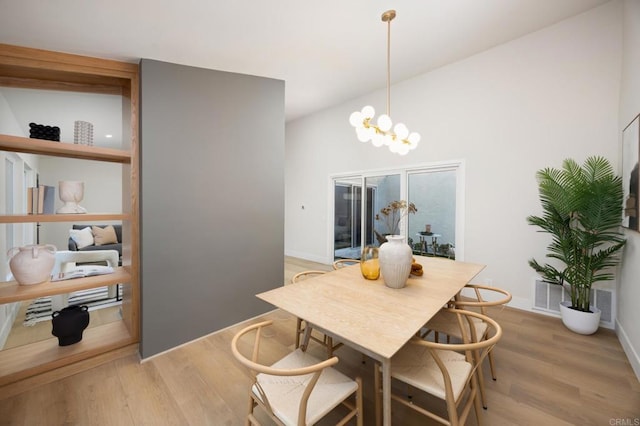 dining space with baseboards, light wood-type flooring, visible vents, and a notable chandelier