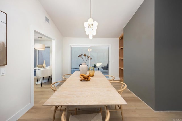 dining room with visible vents, baseboards, vaulted ceiling, light wood finished floors, and an inviting chandelier