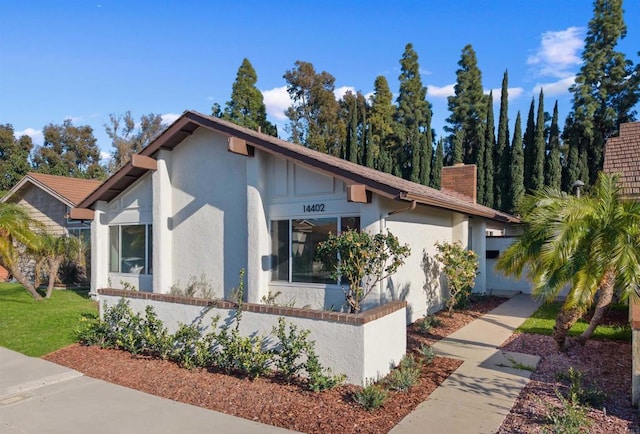 view of front of house featuring a chimney and stucco siding