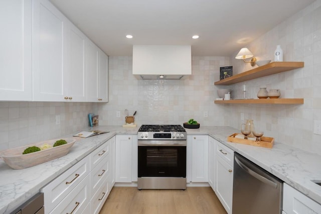 kitchen featuring stainless steel appliances, white cabinetry, decorative backsplash, and light wood finished floors