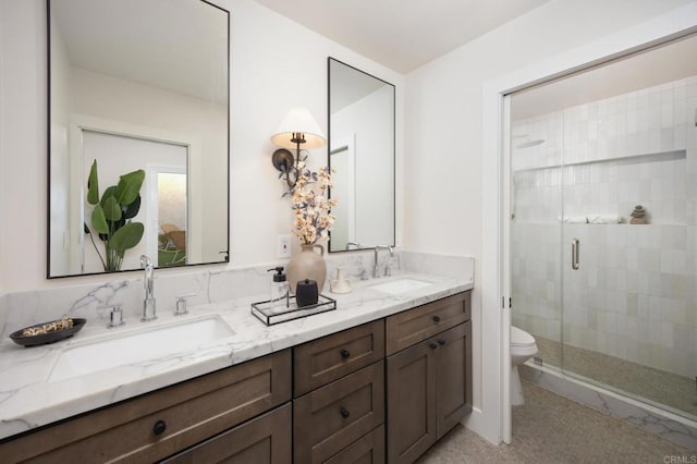 full bathroom with a sink, a shower stall, toilet, and double vanity