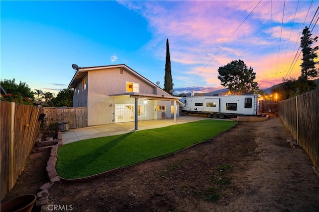 back of house with a patio area, a yard, a fenced backyard, and stucco siding