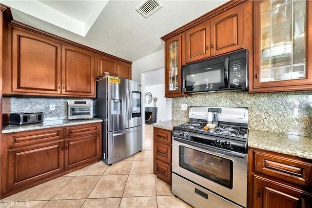 kitchen with light tile patterned floors, visible vents, decorative backsplash, appliances with stainless steel finishes, and light stone countertops