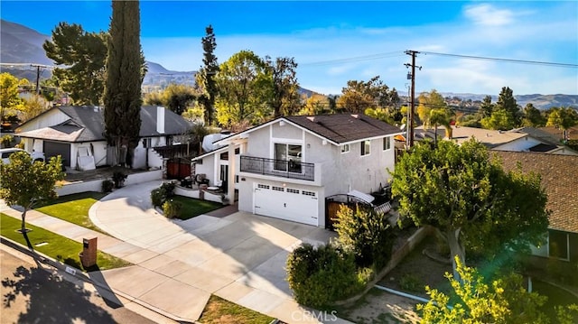 view of front of property with stucco siding, a mountain view, a balcony, a garage, and driveway