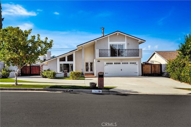 view of front of home featuring a balcony, a garage, fence, concrete driveway, and french doors