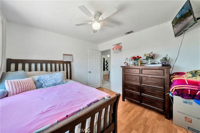 bedroom with light wood-style floors, visible vents, and a ceiling fan