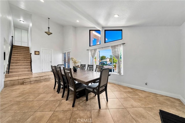 dining space featuring light tile patterned floors, baseboards, and stairs