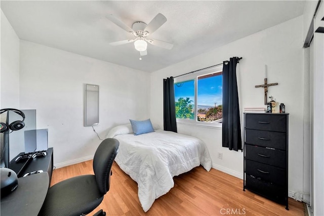 bedroom with a ceiling fan, baseboards, and light wood finished floors