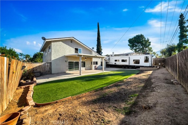 rear view of house with a patio area, a fenced backyard, a yard, and stucco siding