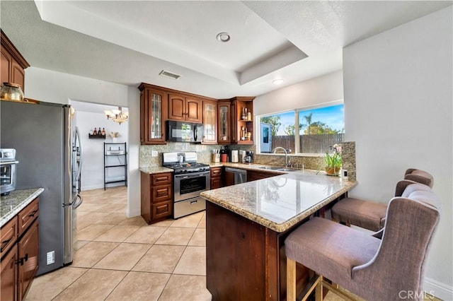 kitchen with stainless steel appliances, a peninsula, a sink, visible vents, and a raised ceiling