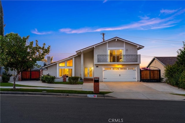 view of front facade featuring stucco siding, fence, a balcony, a garage, and driveway