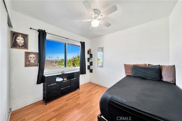 bedroom with ceiling fan, light wood-style flooring, and baseboards