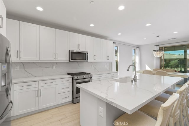 kitchen with decorative backsplash, stainless steel appliances, a kitchen bar, white cabinetry, and a sink