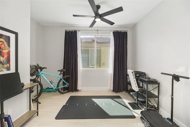 workout room with ceiling fan, baseboards, and wood finished floors