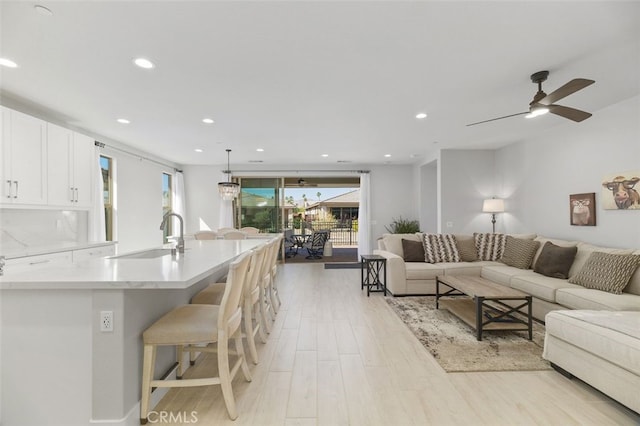 living room featuring light wood-type flooring, a ceiling fan, and recessed lighting