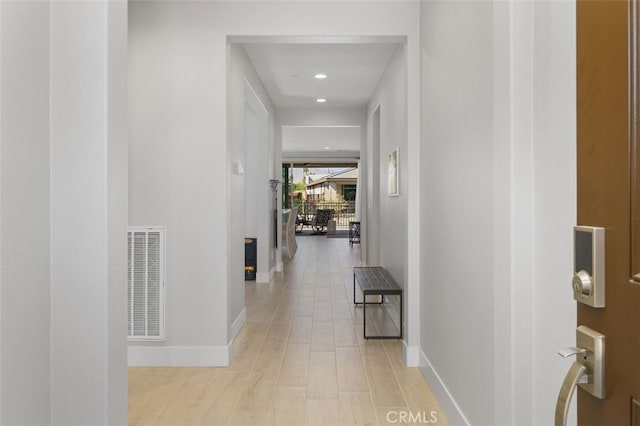 corridor with light wood finished floors, recessed lighting, visible vents, and baseboards