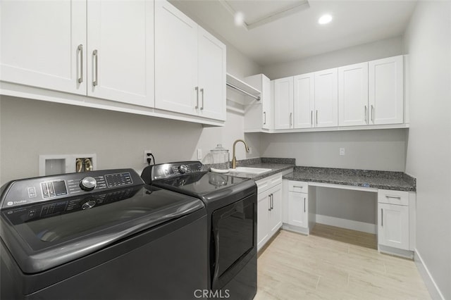 laundry room with a sink, light wood-style floors, baseboards, independent washer and dryer, and cabinet space