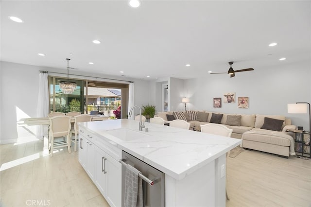 kitchen featuring white cabinets, a sink, light wood-style floors, stainless steel dishwasher, and recessed lighting