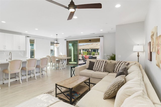 living area with light wood-type flooring, a ceiling fan, and recessed lighting