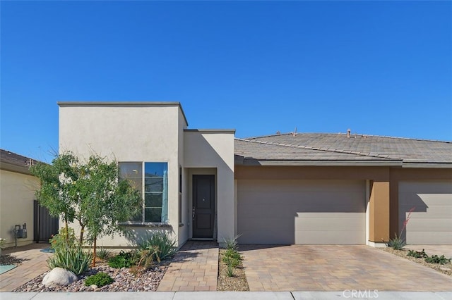 view of front of house with an attached garage, decorative driveway, and stucco siding