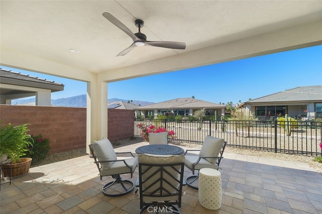 view of patio / terrace with ceiling fan, fence, and a mountain view