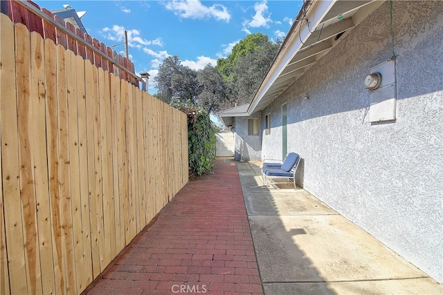 view of side of home featuring a patio, fence, and stucco siding