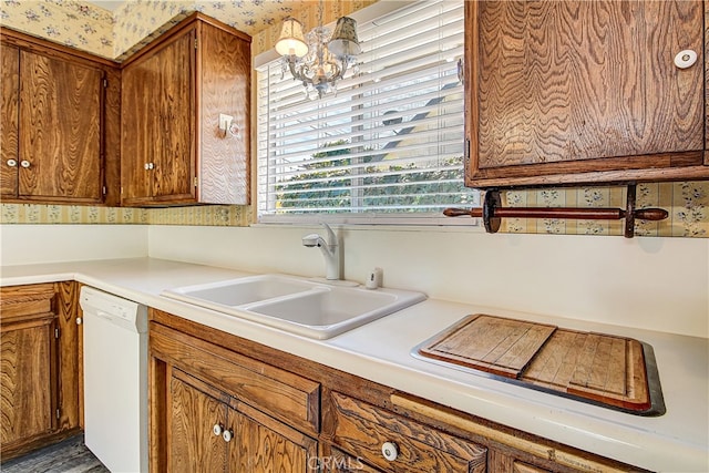 kitchen with brown cabinets, light countertops, white dishwasher, a sink, and wallpapered walls