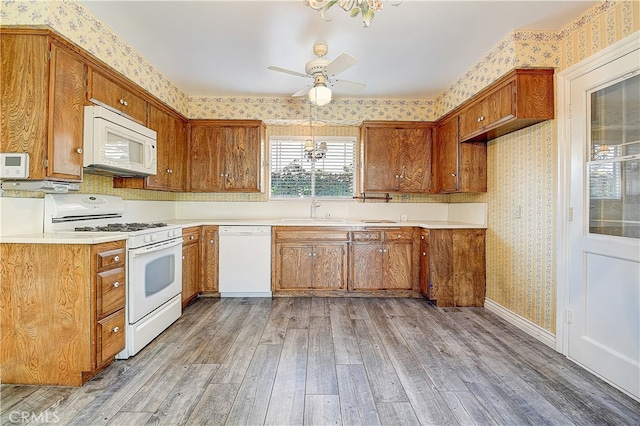 kitchen featuring white appliances, brown cabinets, light wood finished floors, and wallpapered walls