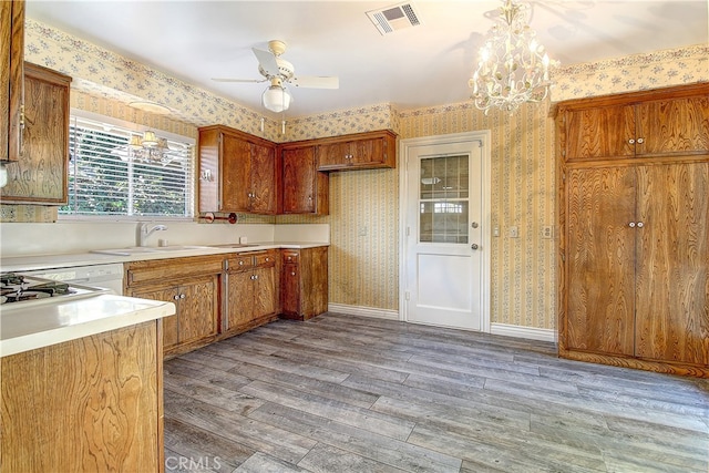 kitchen featuring wallpapered walls, visible vents, brown cabinets, and wood finished floors